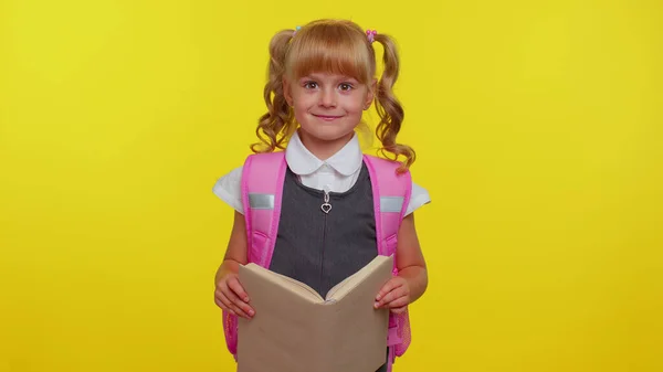 Veselý legrační školačka kluk s knihami oblečený v uniformě nosí batoh s úsměvem na kameru — Stock fotografie