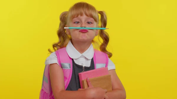 Gracioso niño niña de la escuela primaria haciendo juguetonas expresiones faciales tontas jugando con la pluma — Foto de Stock