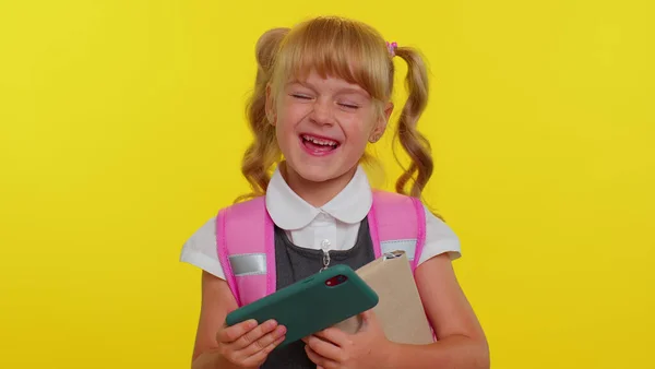 Забавная школьница носит рюкзак с энтузиазмом играя в гоночные видеоигры на мобильном телефоне — стоковое фото