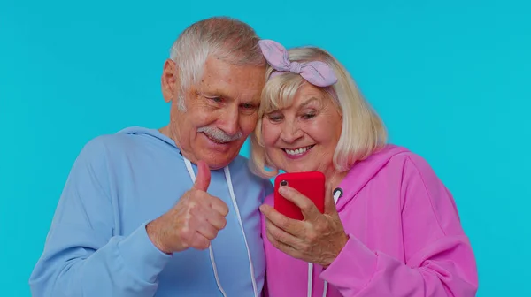 Счастливая пожилая пара мужчина женщина бабушка и дедушка использовать мобильный телефон празднуя выяснилось, большой большой победой новости — стоковое фото