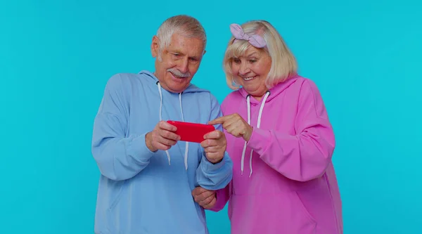 Divertido anciano abuelo moderno abuela jugando simulador de unidad de videojuego en el teléfono inteligente —  Fotos de Stock