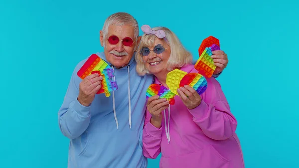 Lachende senior oude grootmoeder grootvader met anti-stress touch screen push pop het populaire speelgoed — Stockfoto