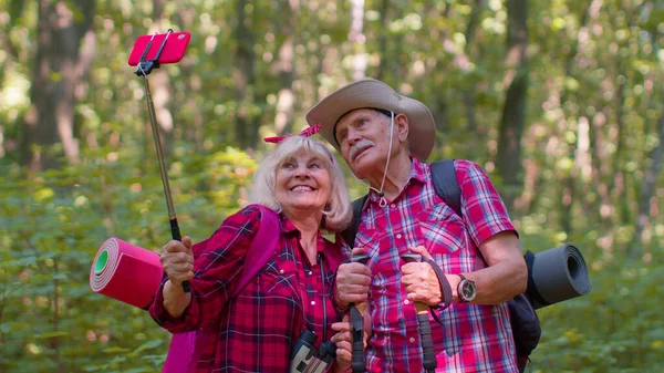 Старшая бабушка дедушка блоггер туристов делает селфи фото портрет на смартфоне в лесу — стоковое фото