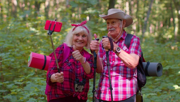 Пожилая бабушка дедушка блоггер туристов делает селфи фото портрет на смартфоне в лесу — стоковое фото