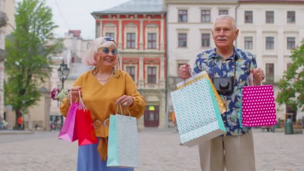 Senior pareja abuela abuelo turistas con bolsas después de compras en el centro comercial durante el Viernes Negro — Vídeos de Stock