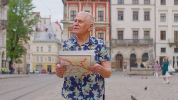 Sénior elegante turista avô homem andando ao longo da rua à procura de maneira usando mapa de papel na cidade — Vídeo de Stock