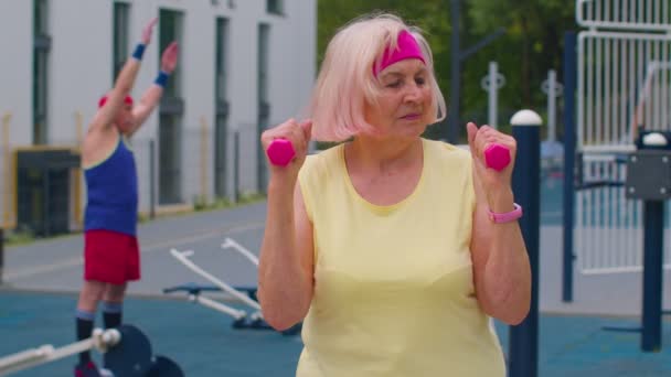 Anziana donna matura nonna facendo allenamento sollevamento pesi esercizio con manubri sul parco giochi — Video Stock