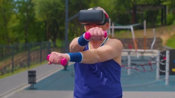 Ηλικιωμένος παππούς σε VR headset do sport προπόνηση fitness stretching άσκηση με αλτήρες — Αρχείο Βίντεο