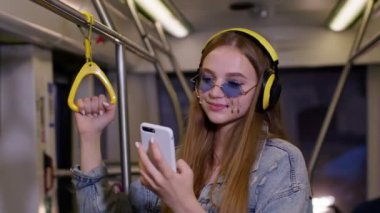 Kulaklık takan, müzik dinleyen genç bir kadın. Şehre otobüsle giderken rahatla, dans et.