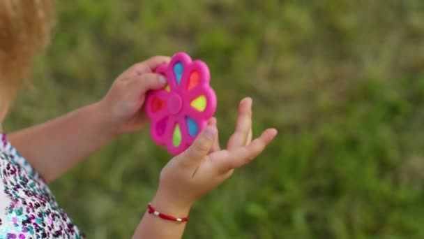 Close-up van meisje spelen spinnen met pop het zintuiglijke anti-stress speelgoed in park, stress angst verlichting — Stockvideo