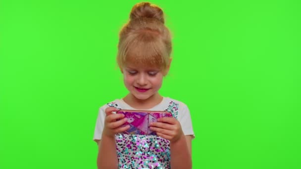 Ребенок девочка проигрывает на мобильный телефон игра, использовать мягкий силикон анти-стресс поп игрушку, чтобы успокоиться — стоковое видео
