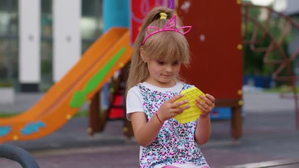 Kind Mädchen Kind spielt Quetschen Anti-Stress-Pop es Spielzeug einfache Grübchen squishy Spiel auf dem Spielplatz — Stockvideo