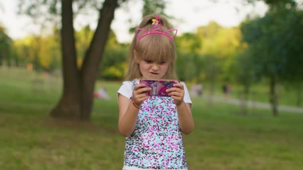 Crianças menina perde no jogo de telefone celular, use silicone squishy anti-stress pop-lo brinquedo para se acalmar — Vídeo de Stock