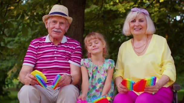 Sorridente nonno anziano nonna con nipote giocare spremendo gioco giocattolo anti-stress — Video Stock