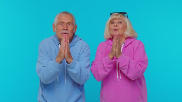 Senior grandfather grandmother in sweatshirts praying, looking upward, making wish, begging apology — Stock Video