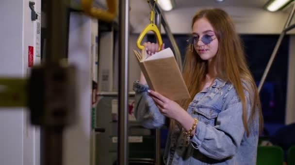 Portret van aantrekkelijke jonge volwassen vrouw verblijf in lege metro trein en het lezen van interessante boek — Stockvideo
