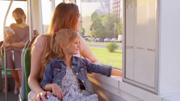 Balades en famille dans les transports en commun, femme avec petite fille s'asseoir ensemble et regarder par la fenêtre tram — Video