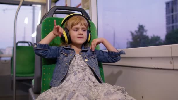 Krásné dítě dívka na sluchátka poslech hudby, relaxovat tanec při cestování autobusem ve městě — Stock video