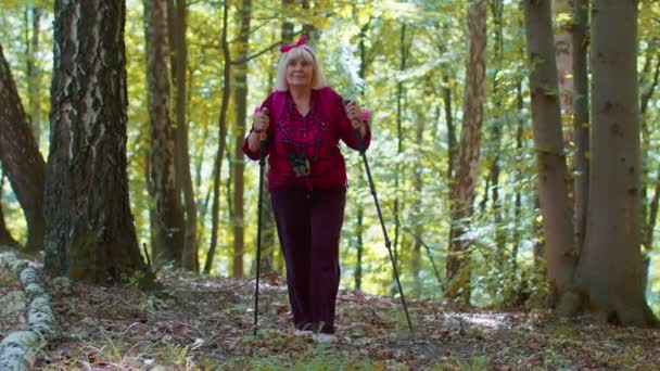 Старша бабуся - турист з Кавказу тренує скандинавську ходьбу з пішоходами в лісі. — стокове відео