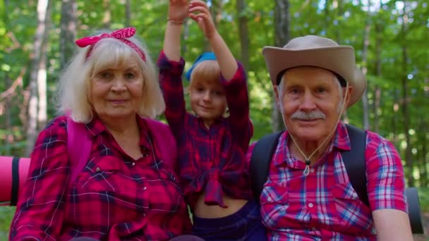 Abuelos ancianos pareja turistas excursionistas descansando en el bosque con su nieta en madera de verano — Vídeos de Stock