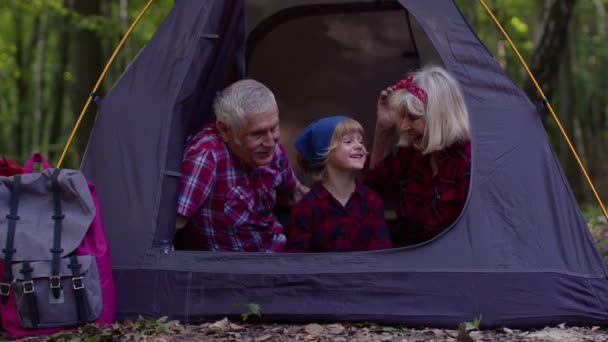 Grand-mère grand-père avec petite-fille assis dans la tente touristique sur le feu de camp dans le bois — Video