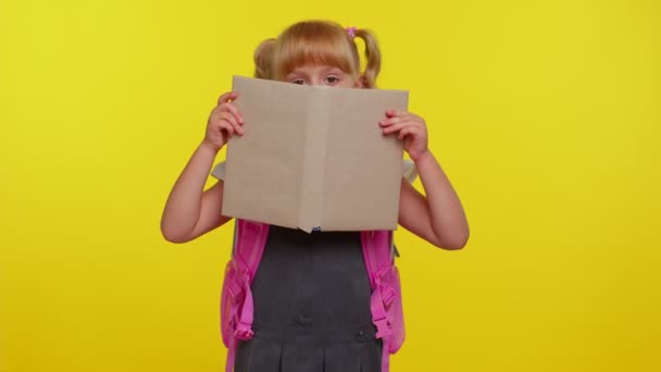 Smiling schoolgirl hiding behind a book laugh fooling around making playful silly facial expressions — Stock Footage Smiling schoolgirl hiding behind a book laugh fooling around making playful silly facial expressions Stock Footage