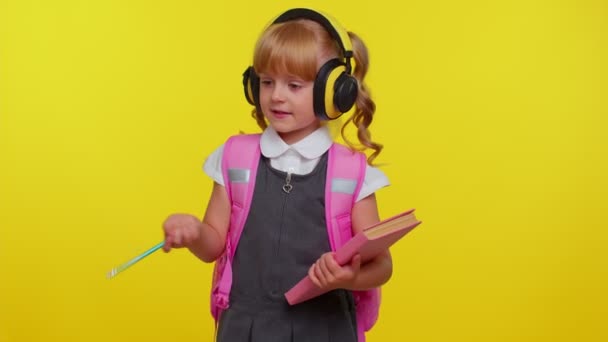 Красивая улыбающаяся девушка в школьной форме слушает музыку через наушники, танцует диско дурачится — стоковое видео
