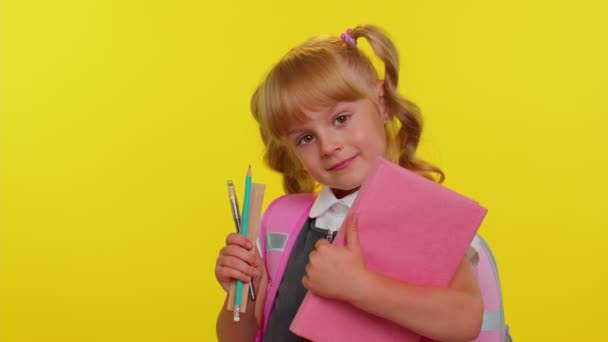 Lucu anak positif gadis sekolah dasar dengan ekor kuda mengenakan seragam tersenyum di latar belakang kuning — Stok Video