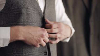 Düğmeli ceket, elleri kapalı, takım elbiseli adam ceketinin düğmelerini bağlıyor ve dışarı çıkmaya hazırlanıyor.