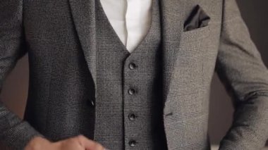 Düğmeli ceket, elleri kapalı, takım elbiseli adam ceketinin düğmelerini bağlıyor ve dışarı çıkmaya hazırlanıyor.
