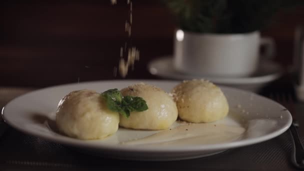 Chef spruzzando noci sul delizioso piatto tradizionale ucraino Gombovtsi gnocchi di formaggio sul tavolo del caffè — Video Stock