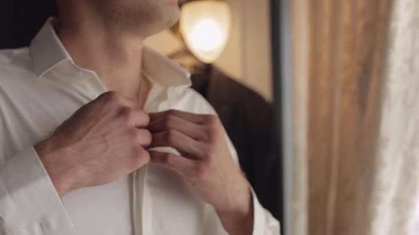 L'uomo elegante in giacca attacca bottoni, abbottonando camicia bianca che si prepara ad uscire vicino a finestra — Video Stock