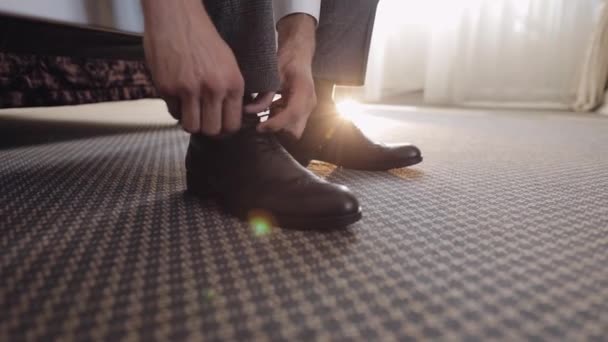 Руки нареченого регулюють, носять, кладуть своє весільне взуття в готельному номері біля вікна — стокове відео