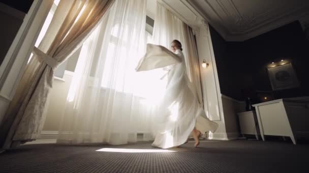 Novia en vestido de tocador cerca de la ventana, preparativos para la mañana de la boda, mujer en vestido de noche y velo — Vídeos de Stock