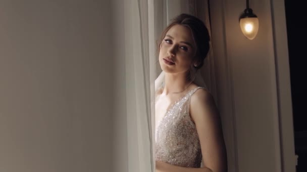 Bride in white dress staying near window and looking up, wedding morning preparations at home — Stock Video