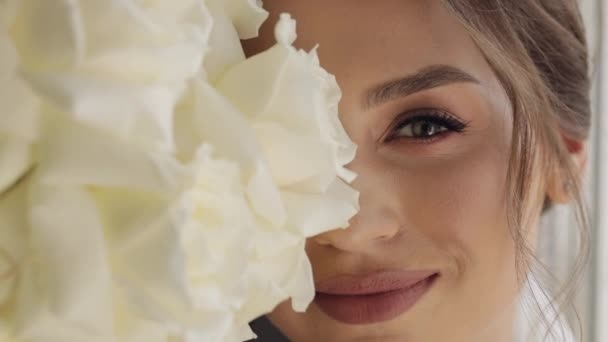 Közelkép a gyönyörű szép, elegáns menyasszony lány néz kamera és mosolygós virágok csokor — Stock videók