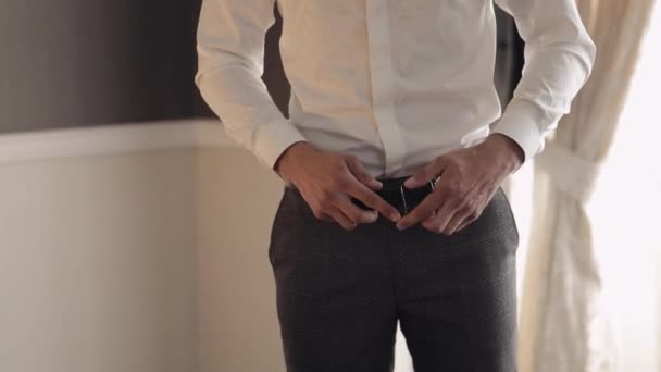 Groom wears belt, man in white shirt puts belt on pants in wedding morning, businessman preparation — Stock Video