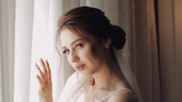Menyasszony fehér ruhában tartózkodik ablak közelében, és várja a vőlegény, esküvői reggeli előkészületek otthon — Stock videók