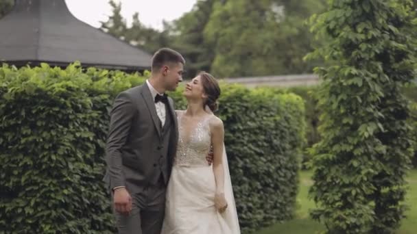 Härliga nygifta kaukasiska brud brudgum promenader i parken, hålla händer, bröllop par familj — Stockvideo