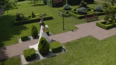 Sevgili yeni evliler, beyaz gelin damat parkta yürüyor, el ele tutuşuyorlar, düğün çifti ailesi.