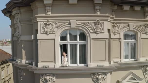 Vista aérea de la novia en vestido de tocador estancia cerca de la ventana boda mañana de la mujer en vestido de noche, velo — Vídeos de Stock