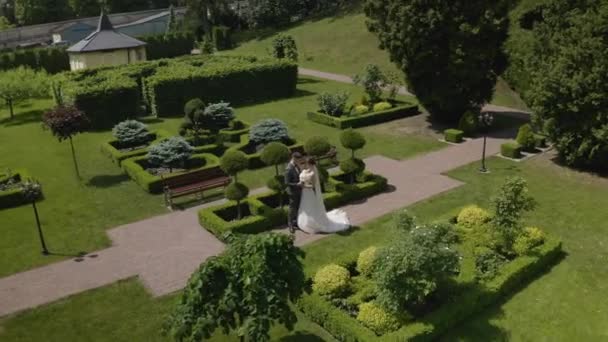 Newlyweds, caucasian groom with bride walking, embracing, hugs making a kiss in park, wedding couple — Stock Video