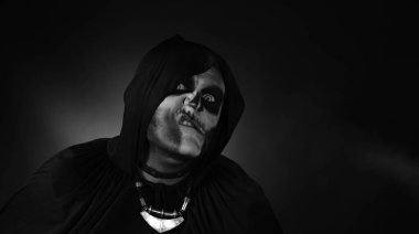 Cadılar Bayramı iskeleti makyajlı uğursuz adam yüzünü ekşiterek kameraya bakıyor, korkutmaya çalışıyor.