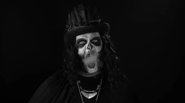 Μοχθηρός άνθρωπος με αποκριάτικο σκελετό μακιγιάζ εκπνέοντας τσιγάρο από το στόμα του και χαμογελώντας — Φωτογραφία Αρχείου