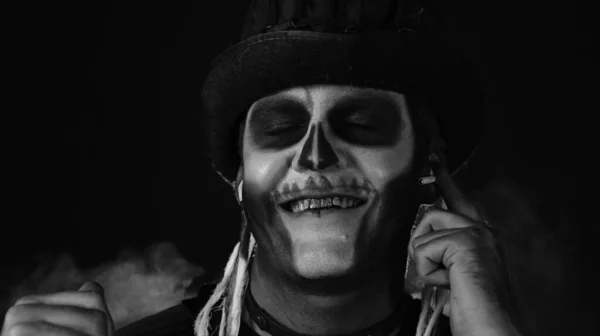 Sinistere man met vreselijke Halloween skelet make-up zet op hoofdtelefoon, begint te dansen, vieren — Stockfoto