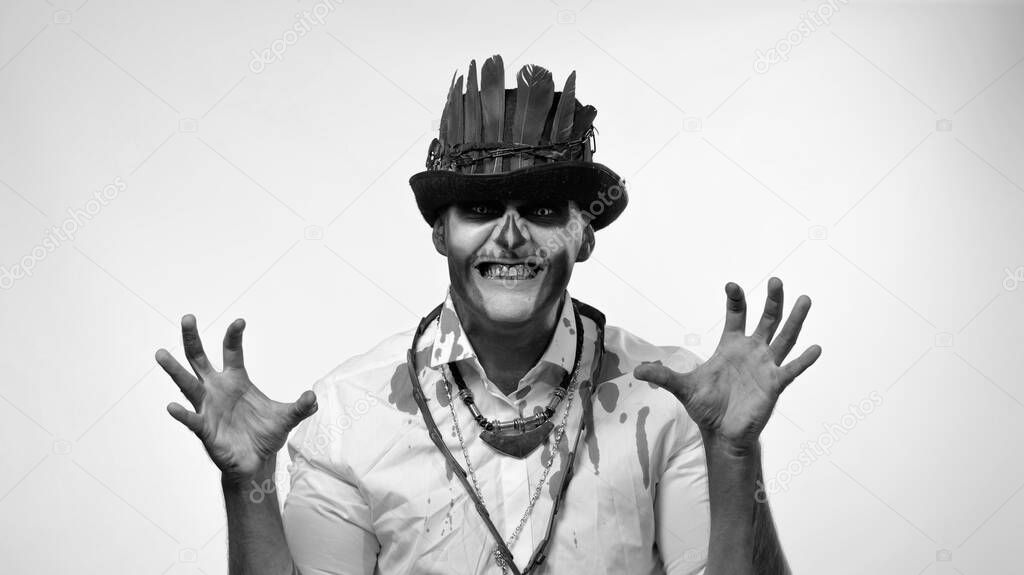 Sinister man with horrible Halloween skeleton makeup making faces, looking at camera trying to scare