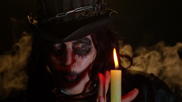 Spaventosa donna anziana raccapricciante con trucco da strega di Halloween guardando candela, evocazione, incantesimo, mago — Video Stock