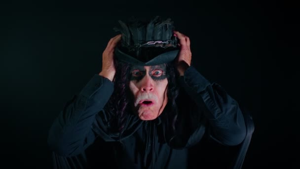 Homem sênior assustador com maquiagem bruxa Halloween levantando as mãos de surpresa, chocado com a vitória — Vídeo de Stock