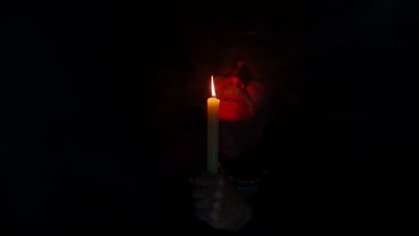 Hombre viejo y siniestro maduro disfrazado de brujo de Halloween haciendo rituales mágicos con vela — Vídeos de Stock