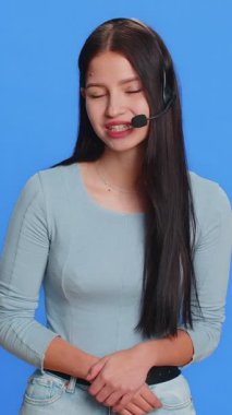 Kafkasyalı, kulaklık takan genç bir kadın, serbest çalışan, çağrı merkezi, destek operatörü yardım hattı, müşteriyle ya da meslektaşıyla konuşmak, iletişim desteği. Mavi arkaplanda izole edilmiş kız